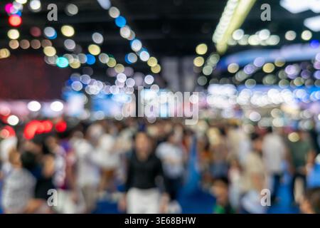 Abstract blurred background of a large crowd attending a major trade show or motor expo. Features colorful bokeh lights and busy atmosphere in a spaci Stock Photo