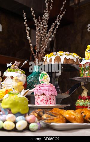 The Easter composition is a pink patterned cake covered with a lush pink icing, decorated with ribbons and a painted egg with a floral motif. Stock Photo