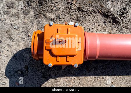 Septic tank connection with an orange storm valve and red pvc pipe system for sewage drainage Stock Photo