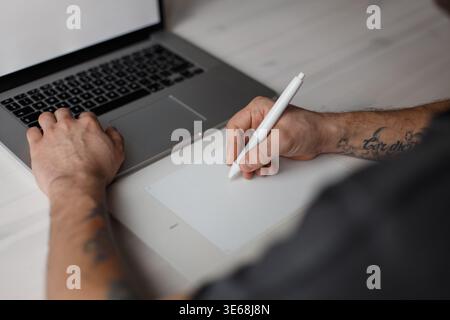Young professional male designer sitting in office and drawing on tablet Stock Photo