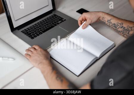 Professional worker designer man sitting near laptop with blank notebook in office Stock Photo