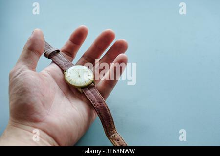 Closeup of old vintage analong wristwatch with aged case brown distressed leather strap in hand palm male Stock Photo