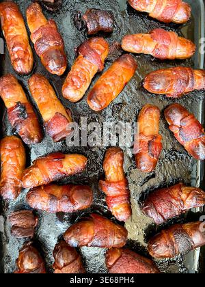 Mini sausages wrapped in bacon or pigs in blankets roasted in a roasting tin Stock Photo