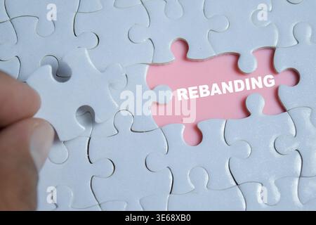 Piece of jigsaw puzzle with word rebranding. A strategic business transformation, identity shift and the missing link in corporate marketing plan Stock Photo