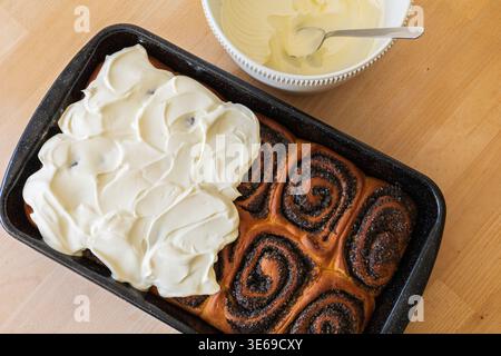 Freshly baked sweet poppy seed rolls topped with creamy frosting made from whipped cream and cream cheese. Homemade dessert concept Stock Photo