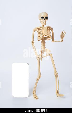 A Playful Skeleton Holding a Smartphone in a Light Background Surrounded by Fun Elements Stock Photo