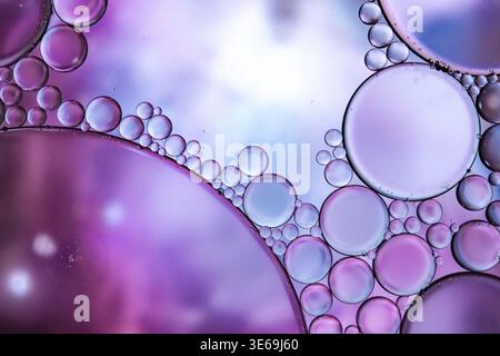 Close-up view of iridescent oil and water bubbles creating a mesmerizing abstract pattern with vibrant purple and blue hues Stock Photo