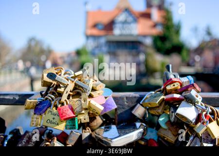 Colourful love locks on bridge railing with historic Gdańsk canal buildings in background, Poland Stock Photo