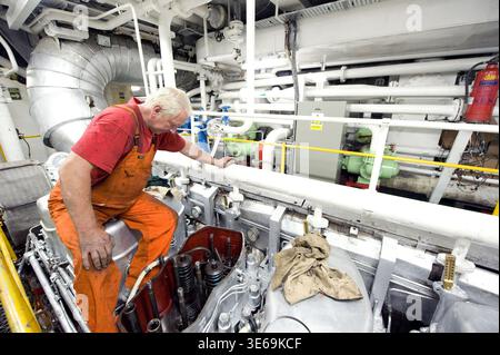 Ship's Engineer & Mechanis working on the Valves and Cylinders of the Vessel's Engine while Moored in Port of Rotterdam, Netherlands. Stock Photo