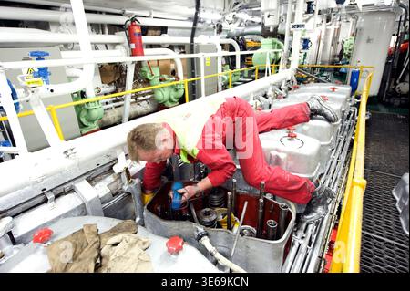 Ship's Engineer & Mechanis working on the Valves and Cylinders of the Vessel's Engine while Moored in Port of Rotterdam, Netherlands. Stock Photo