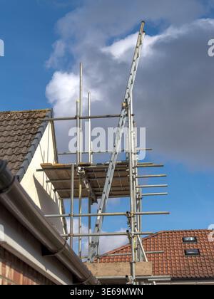 Scaffolding providing access for workers on a residential building roof during renovation Stock Photo