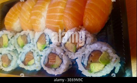 Fresh salmon sushi and maki rolls with avocado, rice, and fish in a plastic container Stock Photo