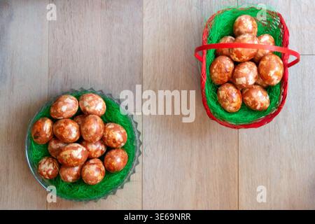 Natural dyed Easter eggs in glass bowl and wicker basket placed diagonally on rustic wooden background with copy space. Traditional holiday compositio Stock Photo