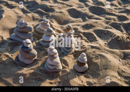 Row of balanced stone pyramids on a sandy beach. Harmony, meditation and zen-like stability concept during summer in Corfu island, Greece. Stock Photo