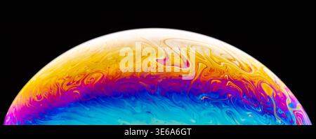 Macro photography captures the iridescent, swirling colors of a soap bubble's surface against a dark background Stock Photo