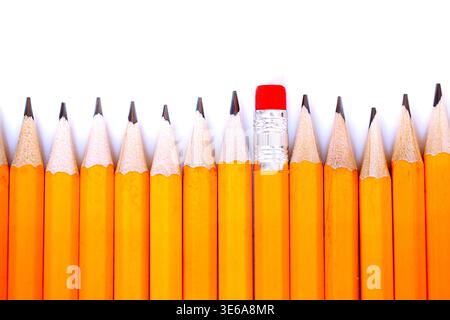 Yellow pencils lined up with one pencil having a red eraser, creating a visual contrast against a clean white background Stock Photo