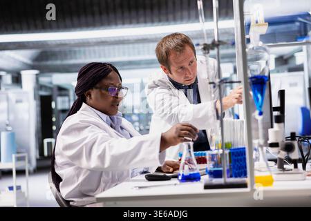 Diverse lab experts collaborating on experiment inside biolab, conducting analysis and examining tissue with advanced equipment. Research study for biotechnology and molecular biology. Stock Photo