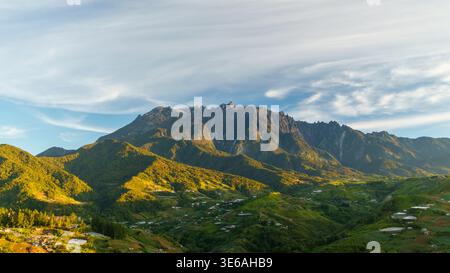 Mount Kinabalu, Sabah, Malaysia – September 21, 2025: A wide view shows Mount Kinabalu rising above forested hills, farmland, and valleys. Stock Photo