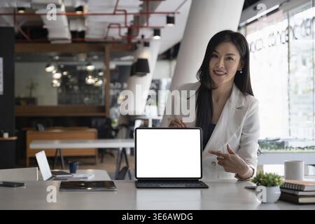 Business woman holding and pointing at digital tablet with blank screen in coffee shop Stock Photo