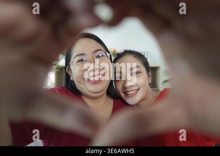 A heartwarming moment between a mother and daughter, showcasing their bond through a heart gesture. Celebrating love and connection Stock Photo