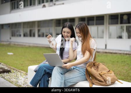 Two university students express joy and excitement as they celebrate a study achievement together, showcasing teamwork and enthusiasm outdoors Stock Photo