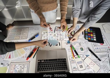 Team collaborating on UX UI design, brainstorming innovative digital interface ideas with sketches and digital tools Stock Photo
