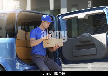 Asian courier with parcel and delivery logistic concept. Delivery man using digital tablet Stock Photo