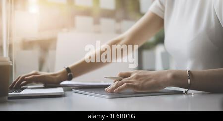 Fashion designer holding stylus pen and using digital tablet and drawing human figure sketches while working at wooden desk in home office Stock Photo