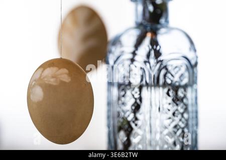 Blown out Easter eggs, a light blue vase in the background Stock Photo