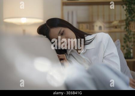 Young asian woman feeling miserable and lonely on sofa at home Stock Photo