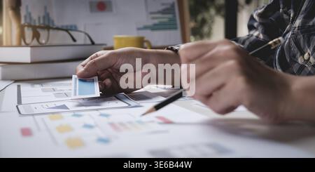 Closeup of female ux developer and ui designer about mobile phone app interface in living room at home.Creative digital development agency concept Stock Photo