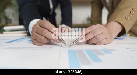 Two business professionals discussing financial data and charts, showcasing teamwork and analysis in a corporate setting Stock Photo