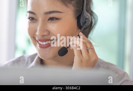 A smiling customer service representative wearing a headset, providing assistance and support to clients over the phone Stock Photo