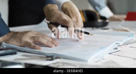 Architects collaborating on house design, reviewing blueprints and planning construction details Stock Photo