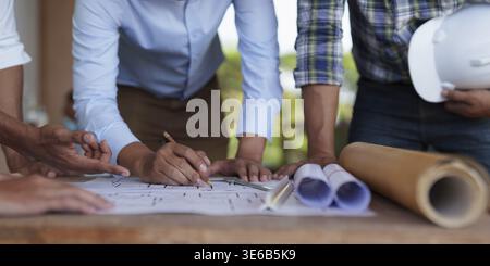 Architect team working with blueprints for architectural plan, engineer sketching a construction project, green energy concept Stock Photo