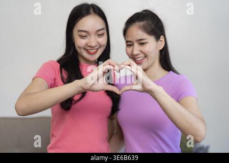 Two women create a heart shape with their hands, showcasing their love and connection while enjoying the moving process, symbolizing unity and joy Stock Photo