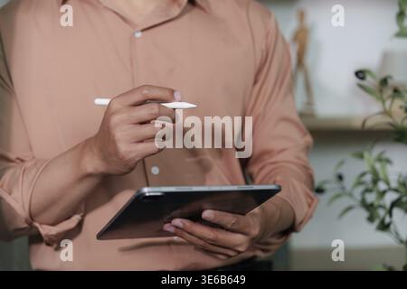 A businessman engages with a tablet, showcasing digital transformation in a modern workspace. Focus on productivity and technology Stock Photo