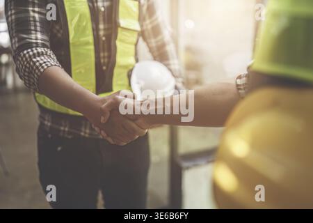Architect and engineer construction workers shaking hands after finish an agreement in the office construction site, success collaboration concept Stock Photo