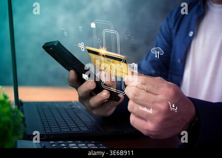 Close-up of hands using a smartphone and credit card above a laptop with a digital lock overlay, illustrating secure online payment, fintech protectio Stock Photo