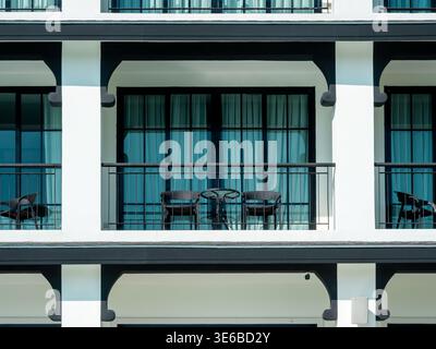 Empty balcony with table and chairs at modern hotel room overlooking resort exterior background. Summer vacation accommodation, travel relaxation, hos Stock Photo