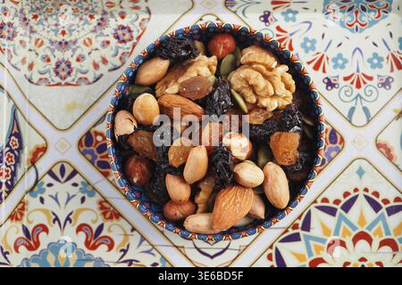 Bowl of mixed nuts and dried fruits on decorative surface Stock Photo