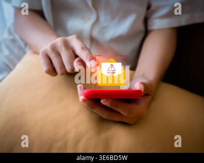 Spam detection and cybersecurity concept. Person using smartphone with spam email warning icon. Symbol of email filter, phishing protection, scam aler Stock Photo