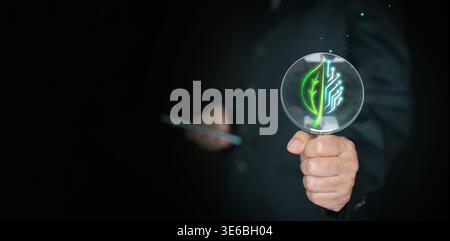 Hand holding a magnifying glass over a green leaf with a circuit icon. Environmental auditing, searching for solutions and sustainability, ESG transpa Stock Photo