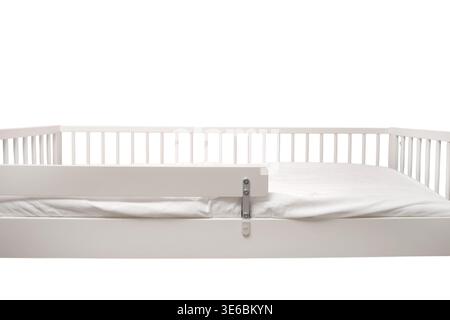 White toddler bed with safety railing isolated on white background. Wooden crib furniture for child bedroom. Safe sleeping environment for kids. Moder Stock Photo