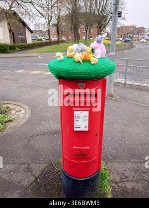A traditional British red pillar box adorned with an Easter knitted "post box topper Stock Photo