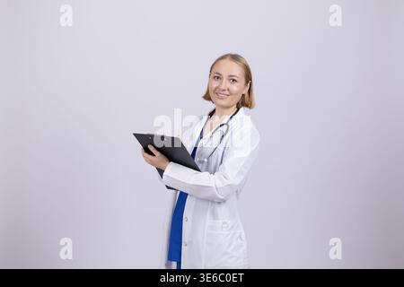 Female doctor in white coat holding digital tablet and smiling Stock Photo