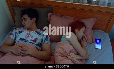 Couple using their smartphones in bed before going to sleep Stock Photo