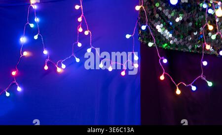 Festive Multi-Colored Globe String Lights on a Blue and Sequin Background Stock Photo