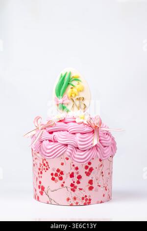 Close-up of pink floral cupcake with Easter egg and XB initials on white Stock Photo