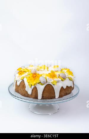 Easter Cake with White Glaze and Yellow Daffodils on Glass Stand Stock Photo